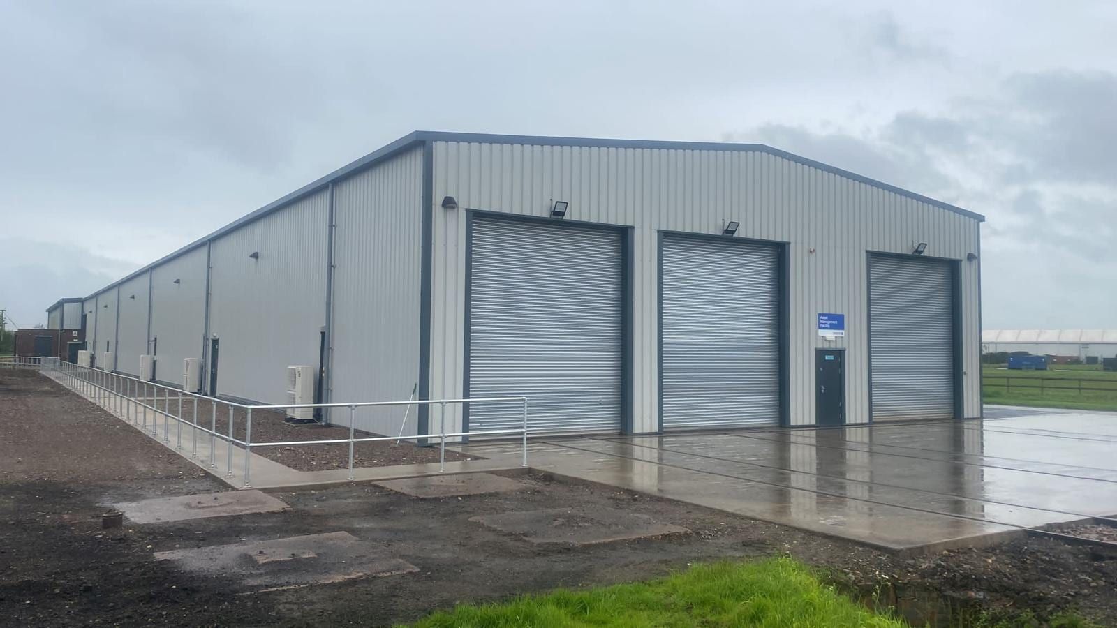 Completed steel clad industrial unit with roller shutter doors and a new concrete apron