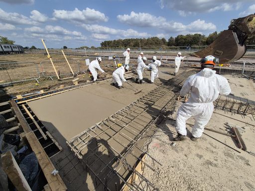 Concrete gang levelling a freshly poured reinforced slab beside a railway line